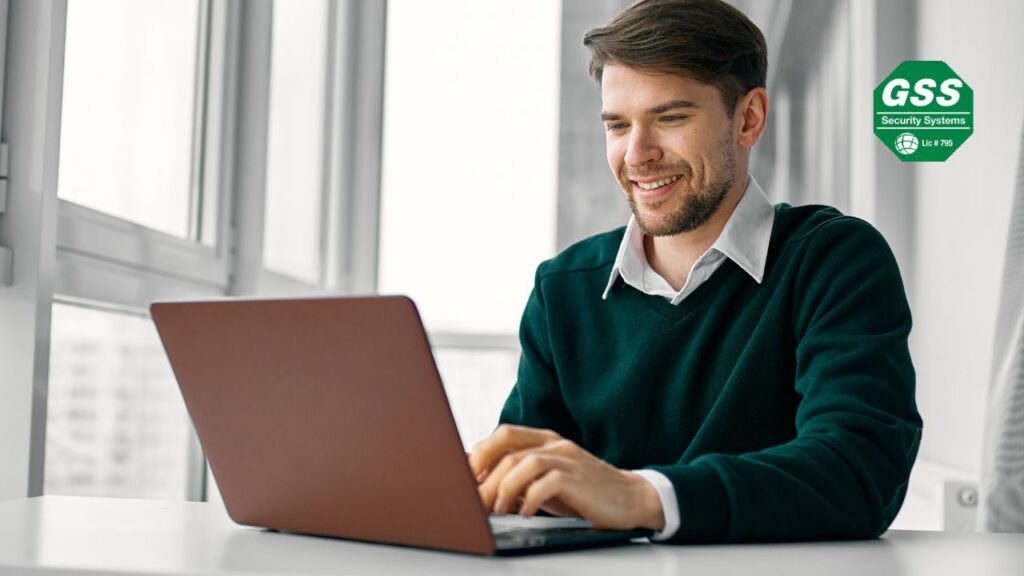A person sitting at a desk, viewing a safe home security company's contact page on a computer screen.